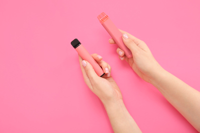 Woman Holding Two Pink Disposable Vape Puff Bars